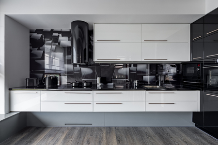 Modern kitchen with white cupboards and black wall tilesの写真素材
