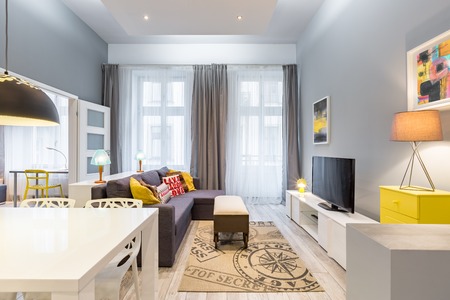 Contemporary home interior with white table, yellow dresser and large sofaの写真素材