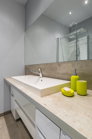 Modern bathroom with countertop basin, big mirror and green accessoriesの写真素材