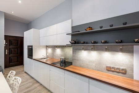 Contemporary white kitchen with wooden countertop and led lightingの写真素材