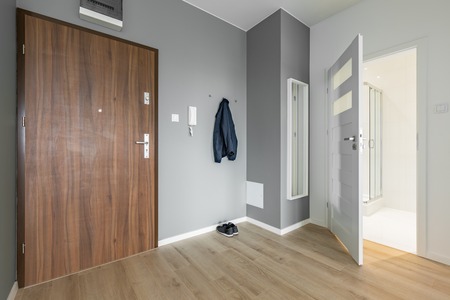 Gray and white entryway with wooden door and mirrorの写真素材