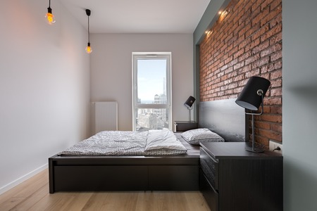 Stylish bedroom with brick wall, double bed and windowの写真素材