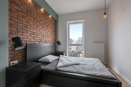 Industrial style bedroom with red, brick wall and double bedの写真素材