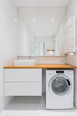 White bathroom with countertop basin, mirror and washerの写真素材