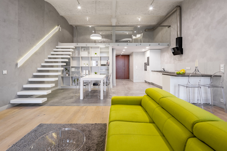 Storied loft apartment with green couch, carpet and transparent coffee tableの写真素材