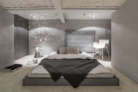 Gray and white bedroom with floor bed and brick ceilingの写真素材