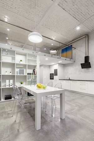 Loft interior with white table, transparent chairs and functional open kitchenの写真素材