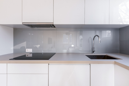White kitchen with gray backsplash, sink and induction hobの写真素材