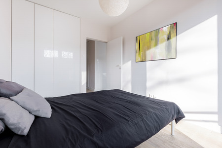 Simple bedroom with white wardrobe and double bedの写真素材