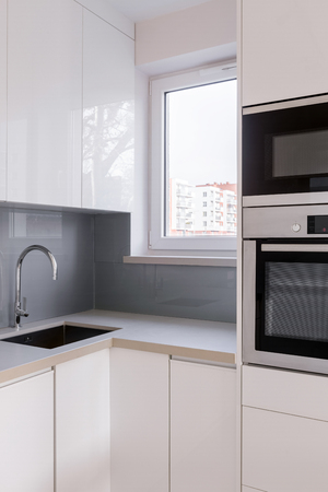 Kitchen with white furniture, sink, gray tiles and countertopの写真素材