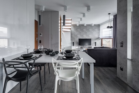 Modern home interior with white table, black tableware and chairsの写真素材