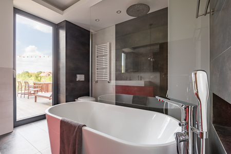 Luxurious bathroom with big bathtub and balcony doorの写真素材