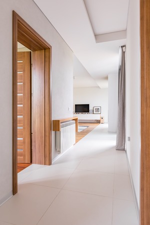 Modern home interior with wooden door, white walls and floor tilesの写真素材