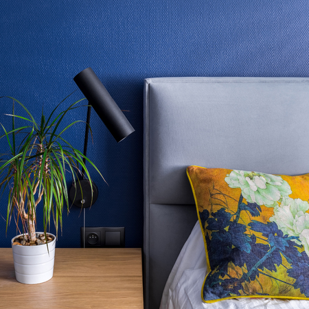 Bedroom with cobalt blue patterned wallpaper, bed and side tableの写真素材