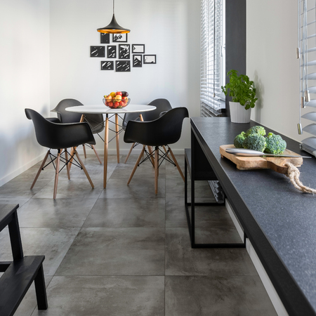 Kitchen with long, granite countertop, concrete floor tiles and round table and chairsの写真素材