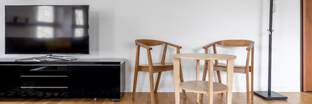 Wooden chairs and table in room with tv screen, panoramaの写真素材