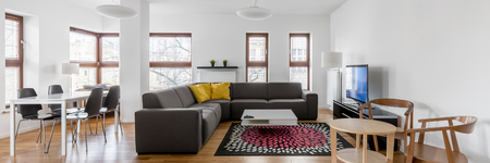 White living room with gray sofa, small dining table and wooden chairs, panoramaの写真素材