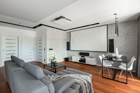Living room with sofa, dining table, white chairs and projector screenの写真素材