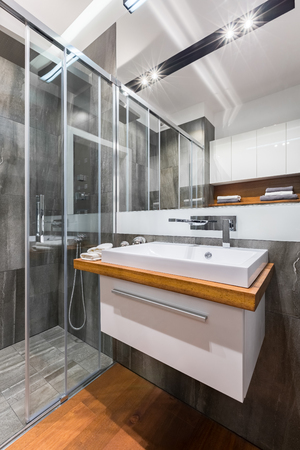 Gray bathroom with white cabinet sink, mirror and walk in showerの写真素材