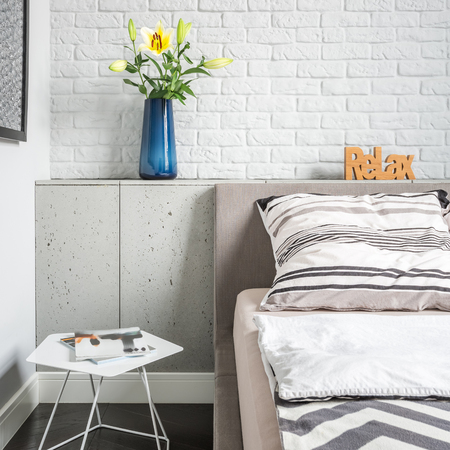 Simple bedroom with white brick wall, bed and side tableの写真素材