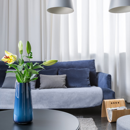 Simple blue vase with flowers on coffee table in living roomの写真素材