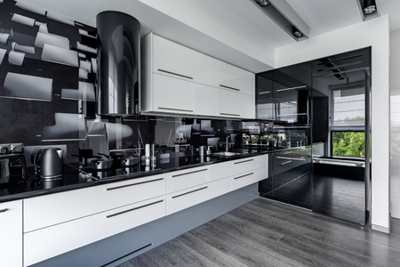 Contemporary and elegant kitchen with white cupboards and black wall tilesの写真素材