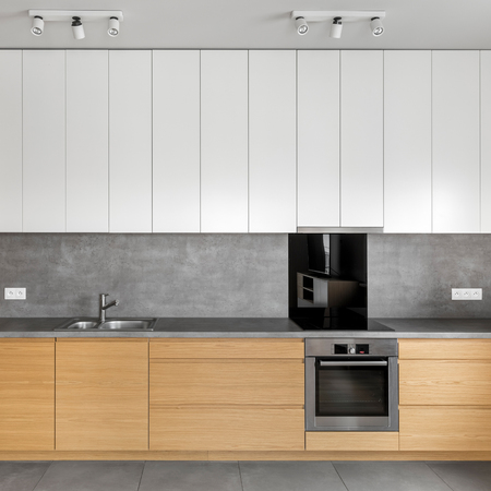 Grey kitchen with wooden cabinets, granite worktop and white cupboardsの写真素材