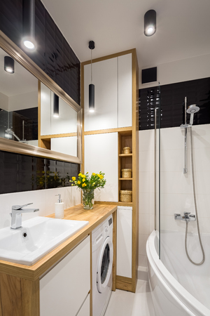 Black and white bathroom with shower and wooden cabinetの写真素材