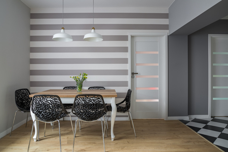 Modern dining room with wooden table, openwork chairs and striped wallの写真素材