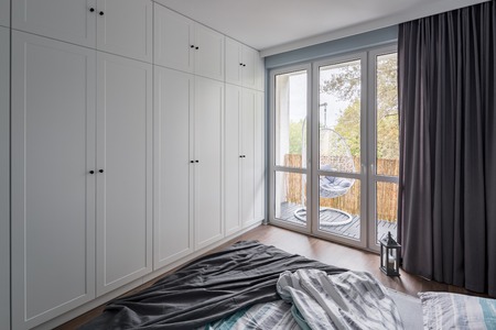 Modern bedroom with big, white wardrobe and windowの写真素材