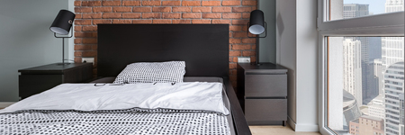 Simple bedroom with double bed, brick wall and big window, panoramaの写真素材