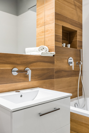 Wooden tiles in bathroom with bathtub, sink and mirrorの写真素材