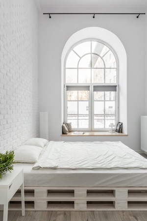 Bed from pallets in loft bedroom with white brick wallの写真素材