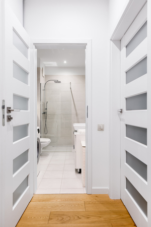 Long hallway with hardwood floor and open door to bathroomの写真素材
