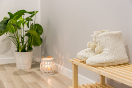 Warm wool slippers on wooden shoe rack in bright hallway