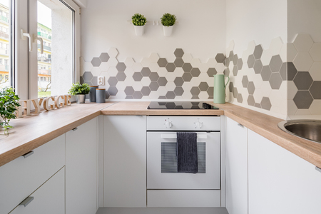 White hygge kitchen with hexagonal tiles, wooden countertop and simple cupboardsの写真素材