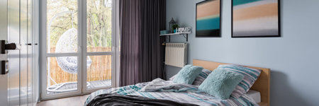 Simple bedroom with double bed and wall paintings, panorama