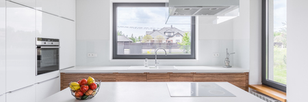 White kitchen with modern island, window and wooden cupboards, panoramaの写真素材