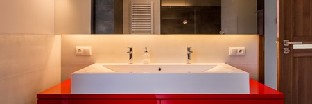 Modern bathroom with double basin, red cabinet and big mirror, panoramaの写真素材
