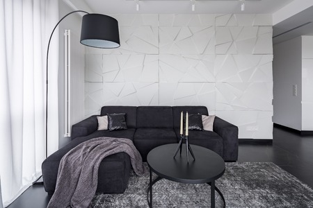 Black corner sofa, coffee table and arc floor lamp in modern apartmentの写真素材