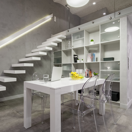 Loft interior with white table, transparent chairs and bookcaseの写真素材