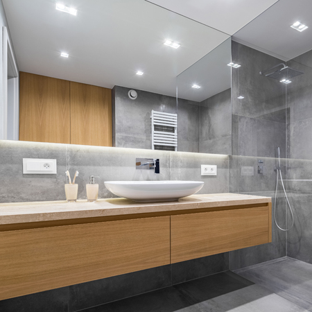 Modern bathroom with wooden countertop, shower, basin and big mirrorの写真素材
