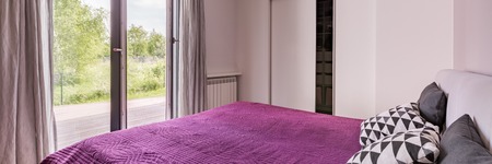 Panoramic view of elegant bedroom with double bed, violet bedding and closetの写真素材
