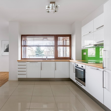 Modern open kitchen with white cupboards and big windowの写真素材