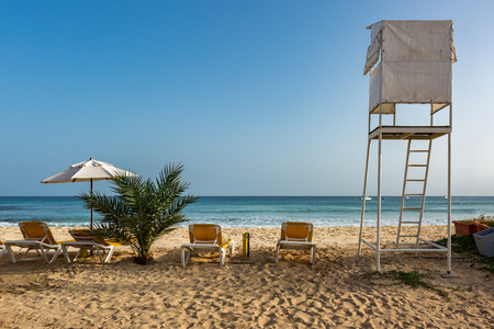 Sunbeds and umbrella next to lifeguard stand on the beach in Santa Maria, Sal, Cape Verde, Cabo Verdeの写真素材