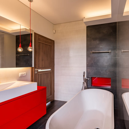 Square frame of modern bathroom with bathtub and red cabinets