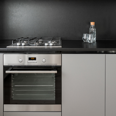 Gray kitchen cabinet, black backsplash, oven and hobの写真素材