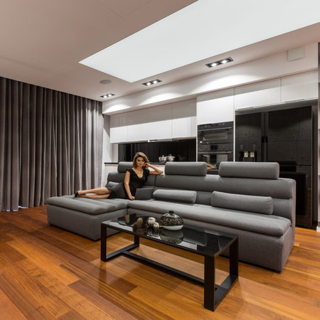 Woman lying on gray sofa in modern apartment with black coffee table