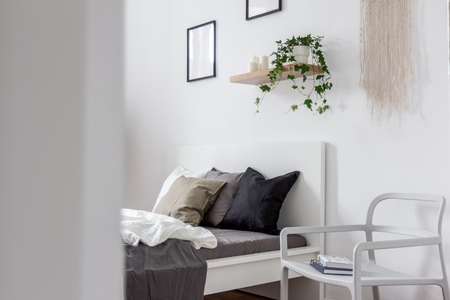 Modern bedroom interior with simple bed and stylish white chairの写真素材