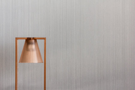 Modern and elegant copper lamp standing beside striped wallの写真素材